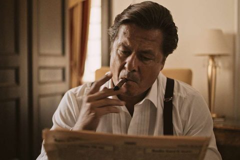 Eleganter Herr der 50er Jahre raucht eine Zigarre und liest eine Zeitung in einem Hotelzimmer