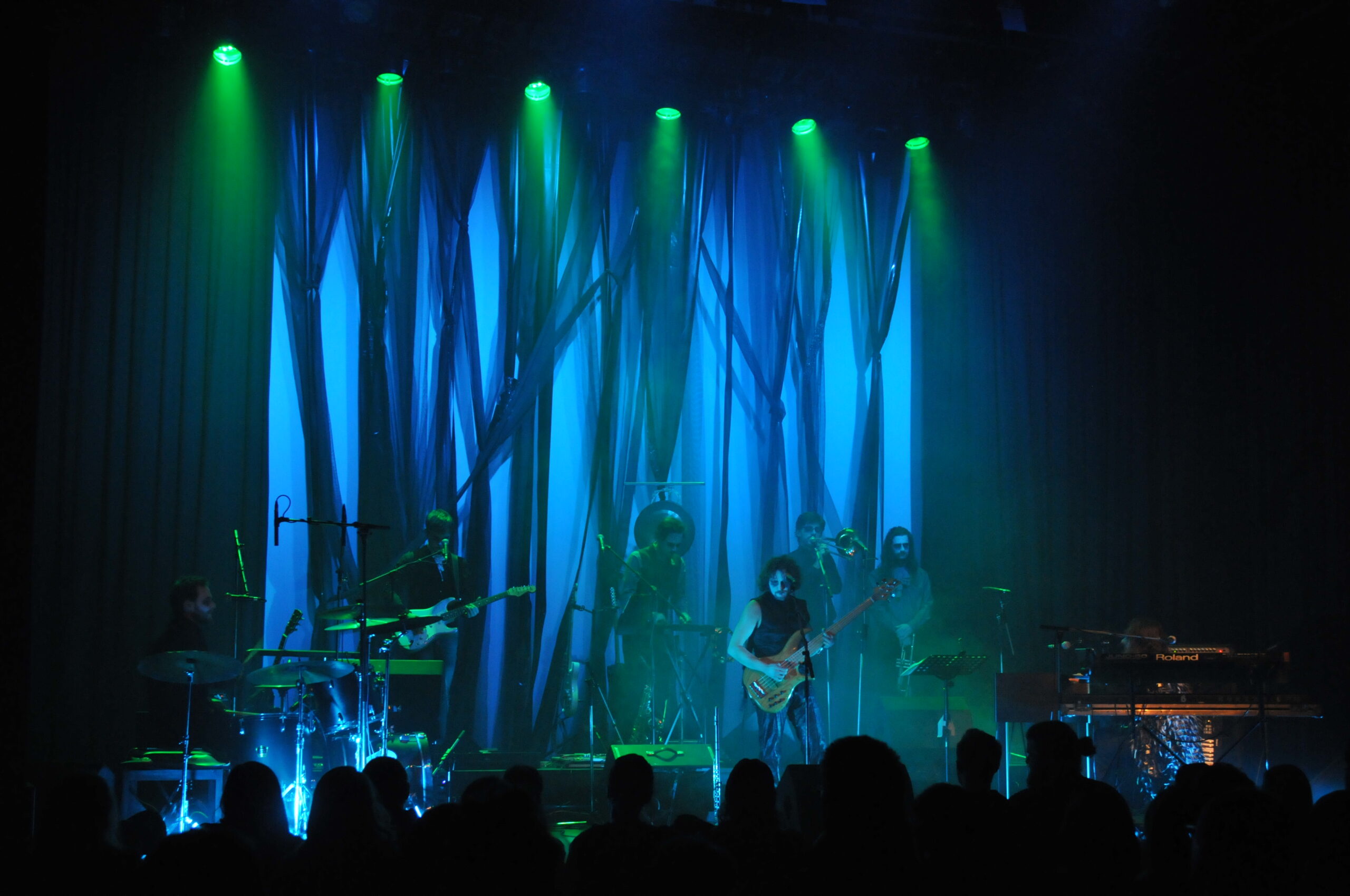 Bühnenbild und Kostümbild Konzert „Unterwelt“, türkis beleuchtete, mystische Bühneninstallation mit Musikern