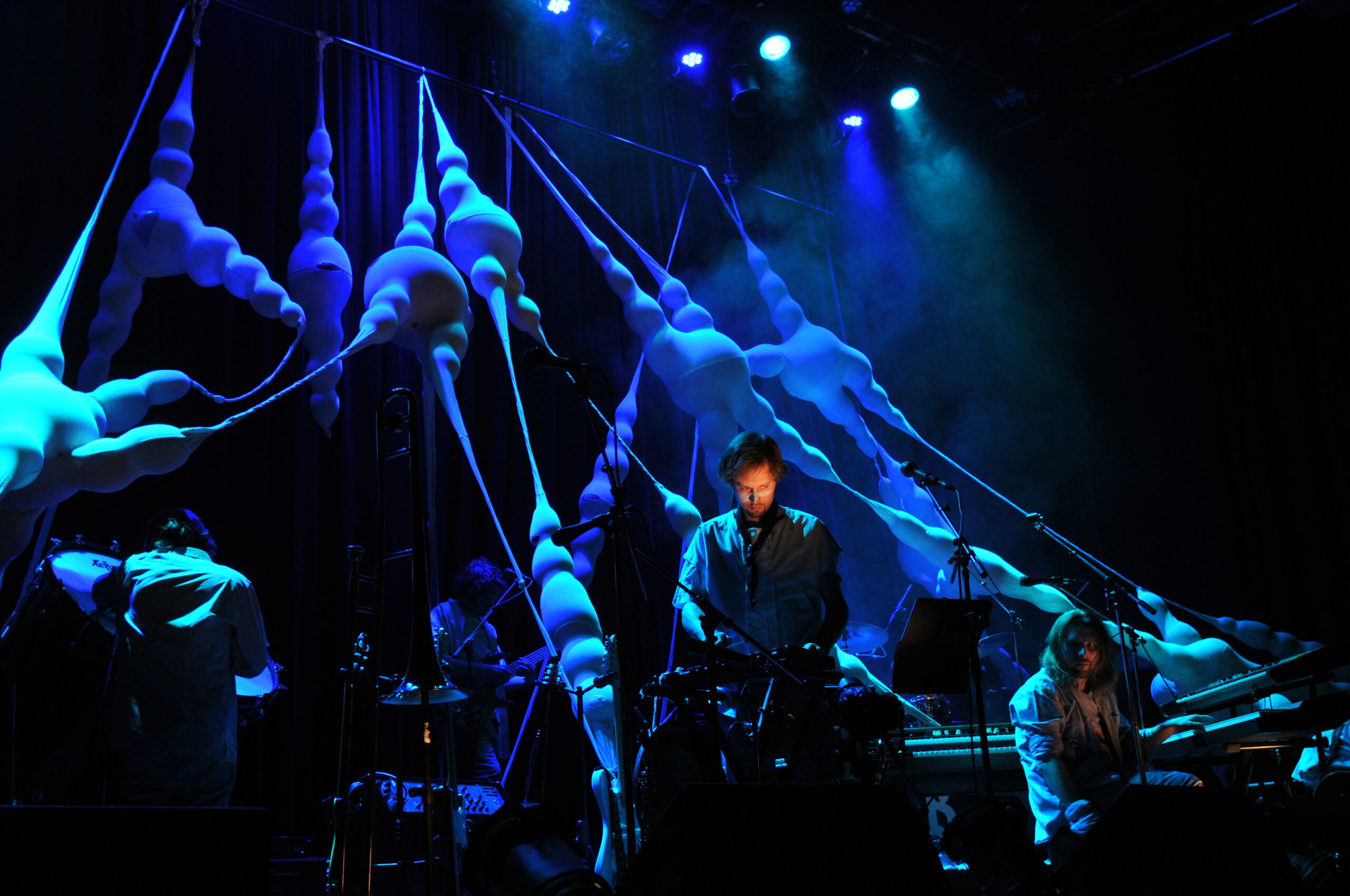 Bühnenbild und Kostümbild Konzert „Krásná Hora“, beleuchtete, organische Bühneninstallation, die sich quer über die Bühne spannt, im Vordergrund ein Musiker