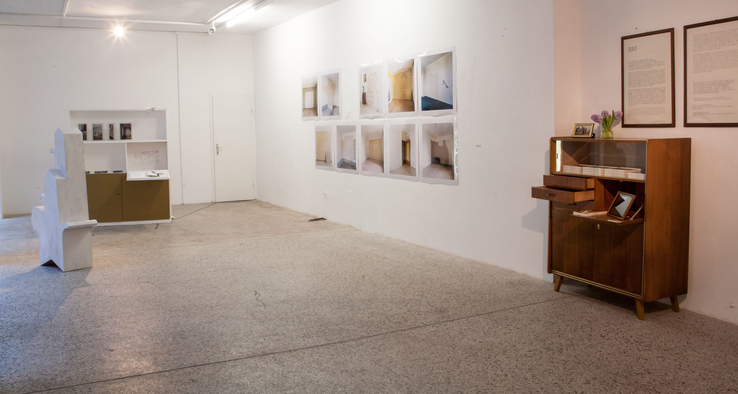 Ausstellungsgestaltung Raumdesign – Design Ausstellung Wien „Halt mich fest. Frier mich ein. Zeig mich her.“, Ansicht eines Raumes mit Bildern an der Wand und zwei Schränken mit verschiedenen Kunstwerken