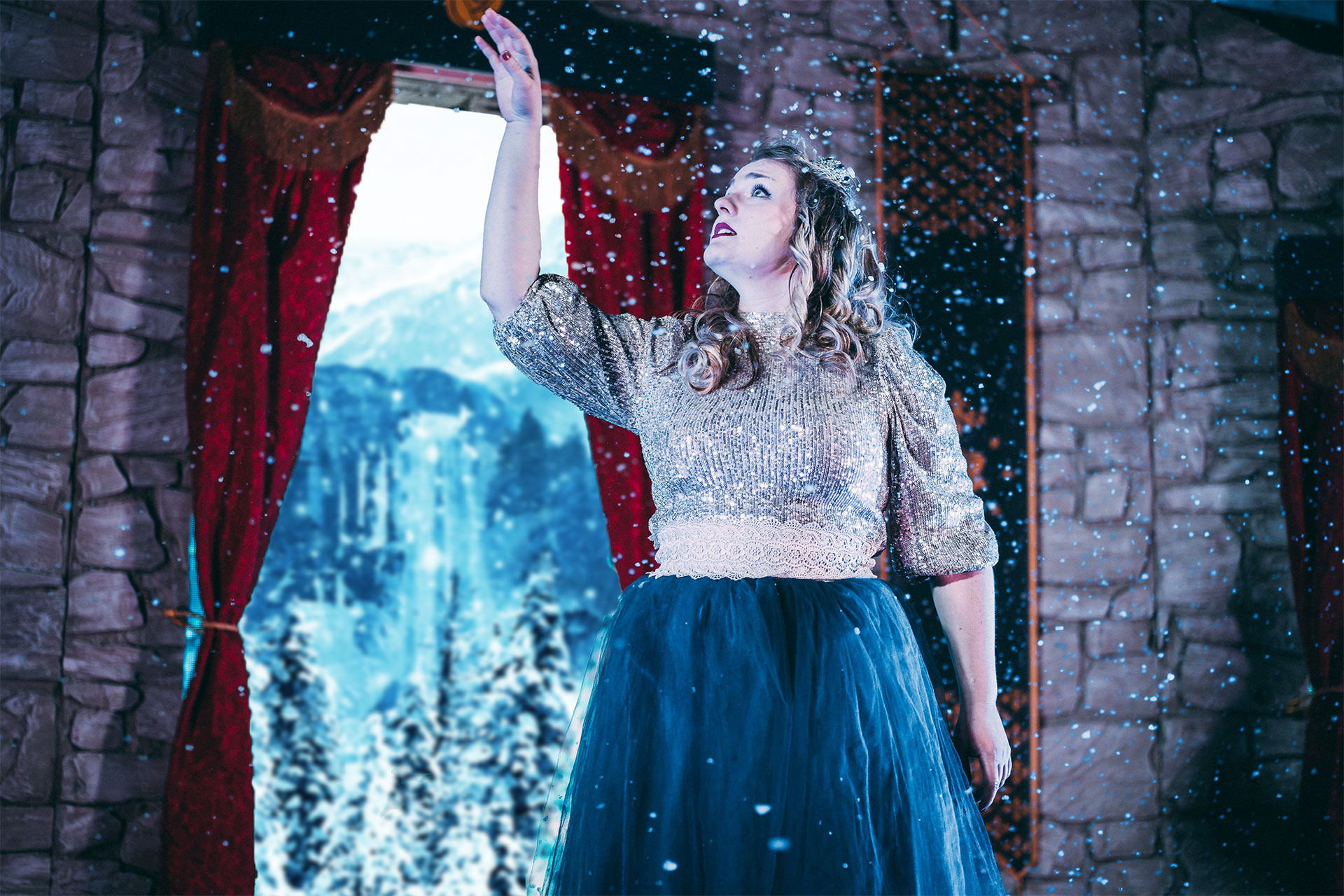 Es schneit, eine Prinzessin steht im Schnee vor einem Fenster, das eine Winterlandschaft zeigt