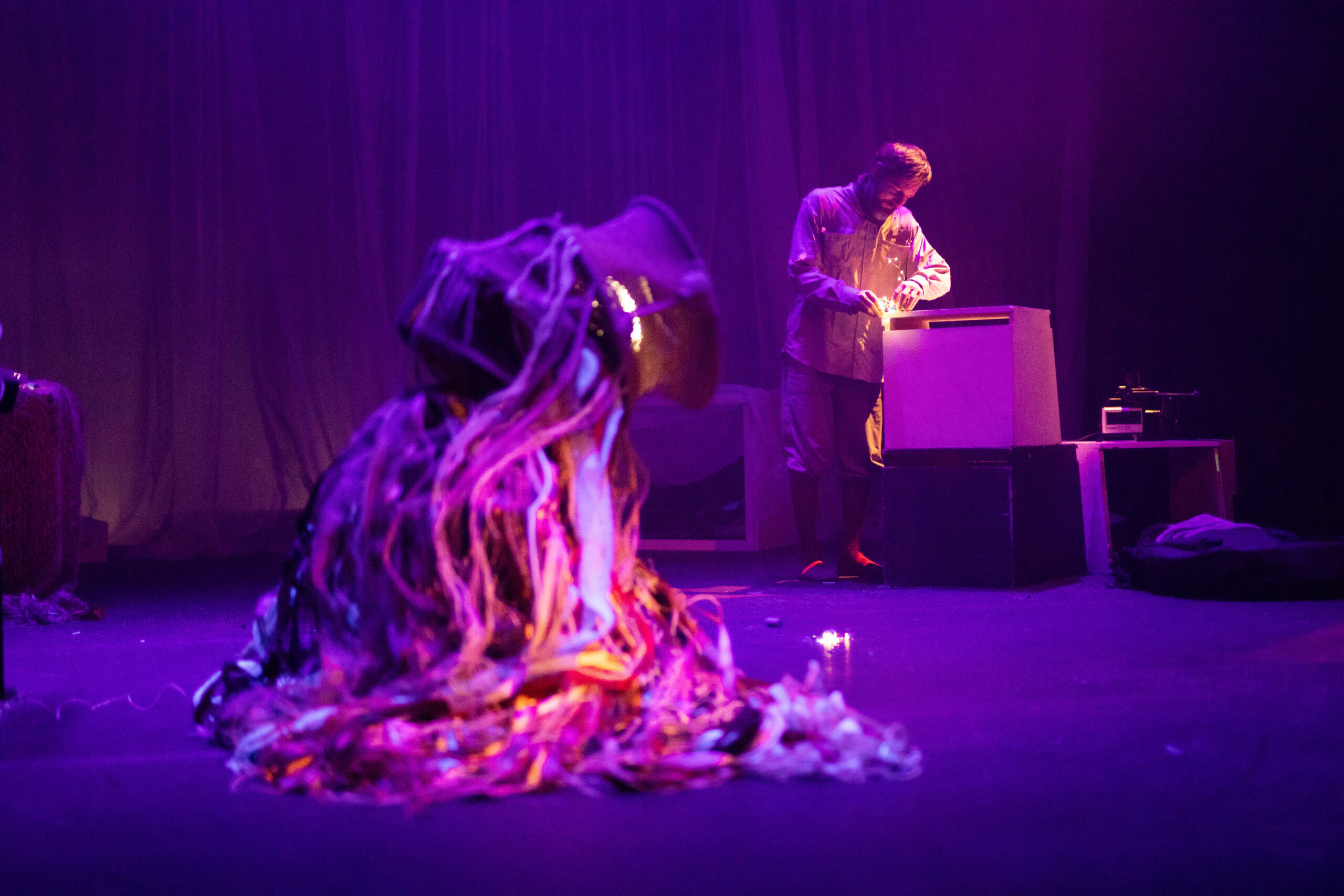 Ein seltsames Wesen beobachtet einen Mann, der ein Licht an einer Kiste untersucht