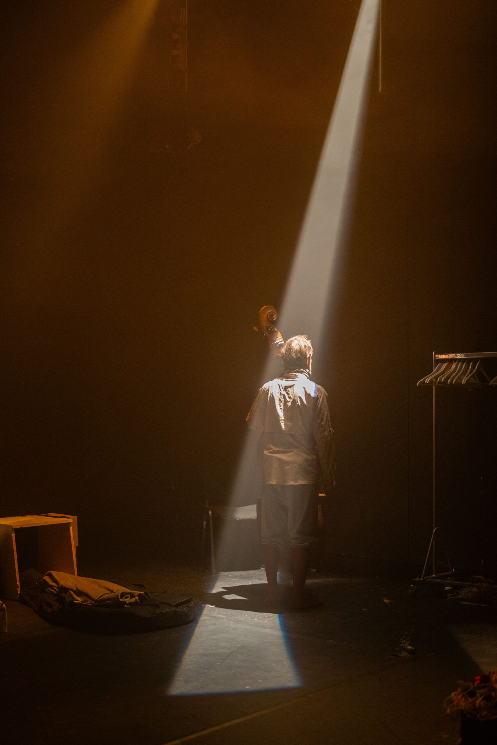 Bühnenbild und Kostümbild Theater – Tanztheater „The Collapse“, ein Mann mit Kontrabass in der Hand im Scheinwerfkegel