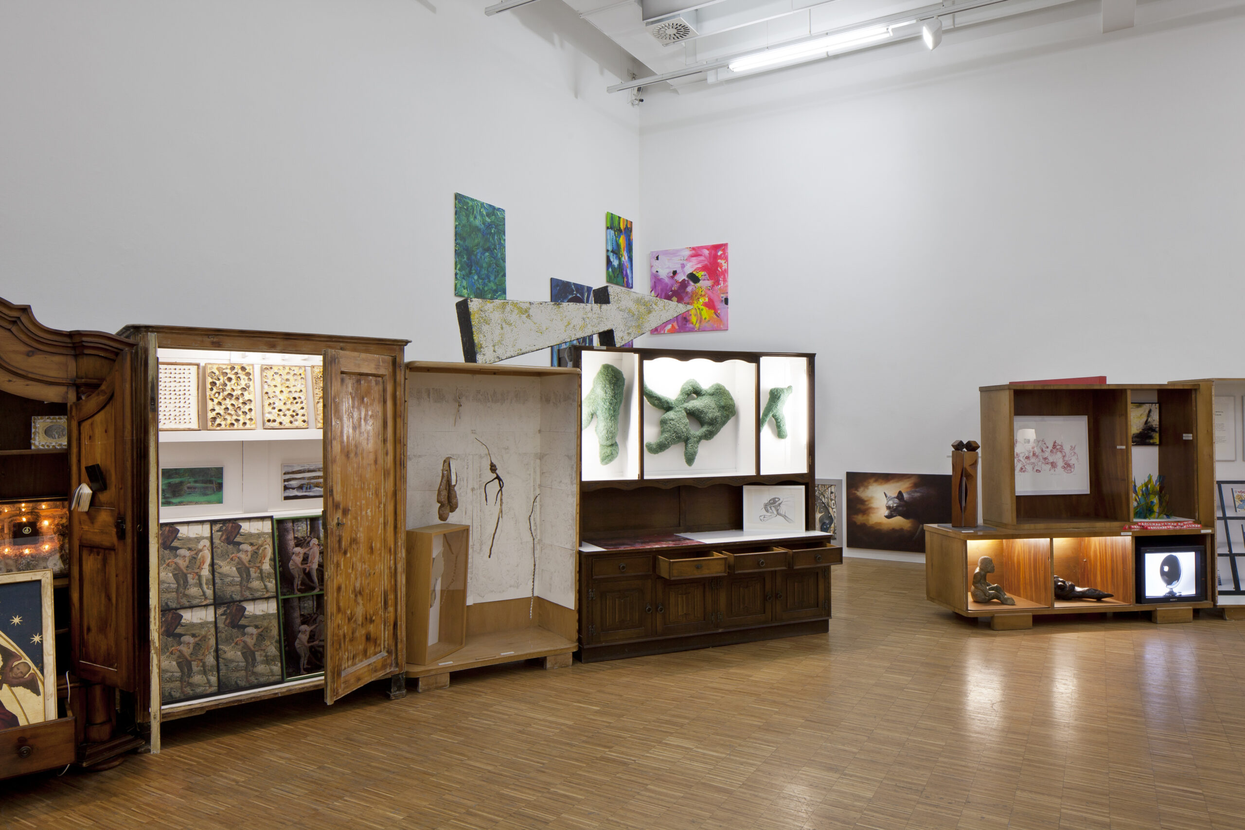 Ausstellungsgestaltung Raumdesign – Design Jahresausstellung „Für die Fülle“, ein Ausstellungsraum wie eine Wunderkammer: mit alten Schränken, in denen sich verschiedene Kunstwerke befinden